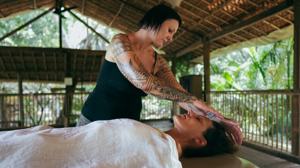 Zdjęcie przedstawiające Ewę Kaniewską trzymającą ręce nad głową klientki, podczas masażu Lomi Lomi Nui.
